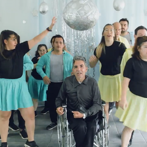 imagen donde se ve un grupo de personas con discapacidad bailando. En el centro, un varón en silla de ruedas, alrededor, hombres y mujeres del grupo Baila conmigo, bailando alrededor