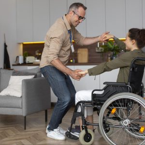 Imagen ilustrativa. Una mujer joven en silla de ruedas bailando con un hombre