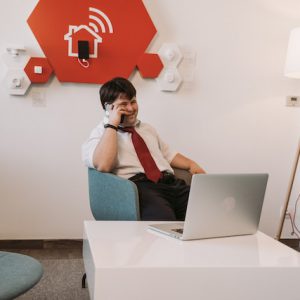Persona con discapacidad en ámbito laboral, frente a una computadora hablando con el celular